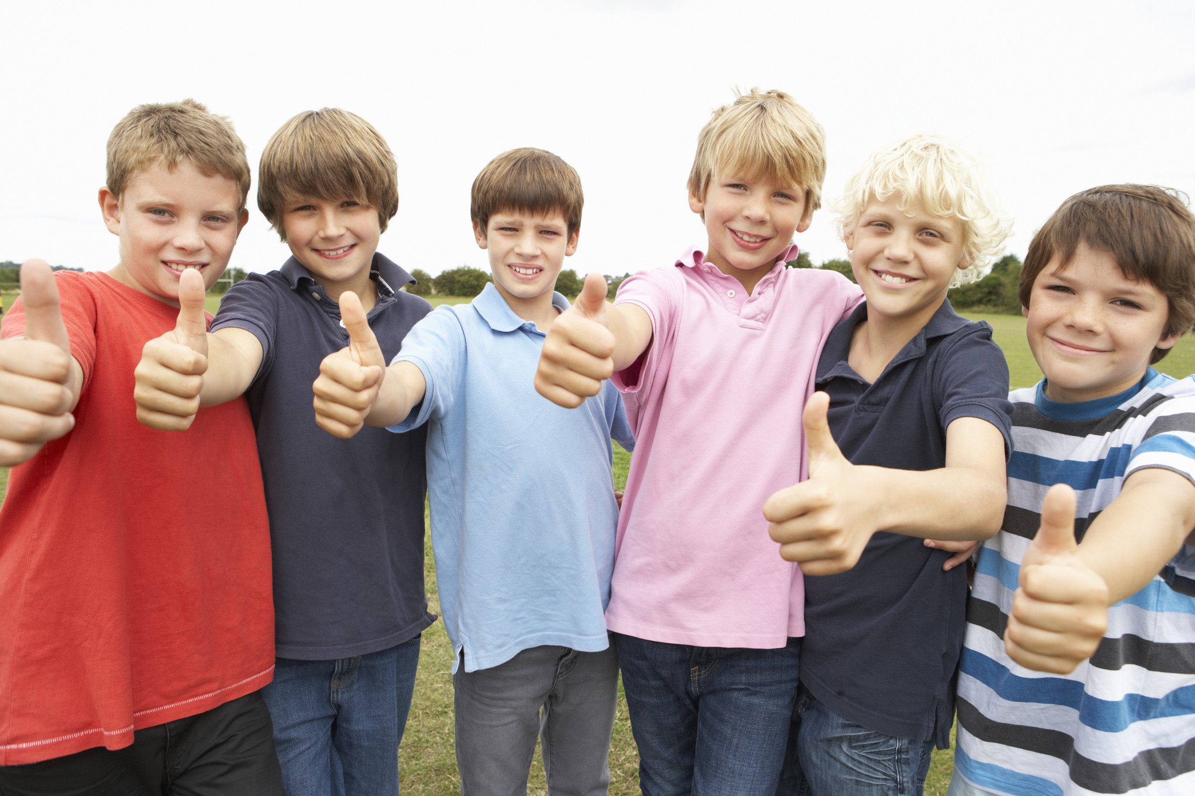 Portrait group of boys doing thumbs up in park